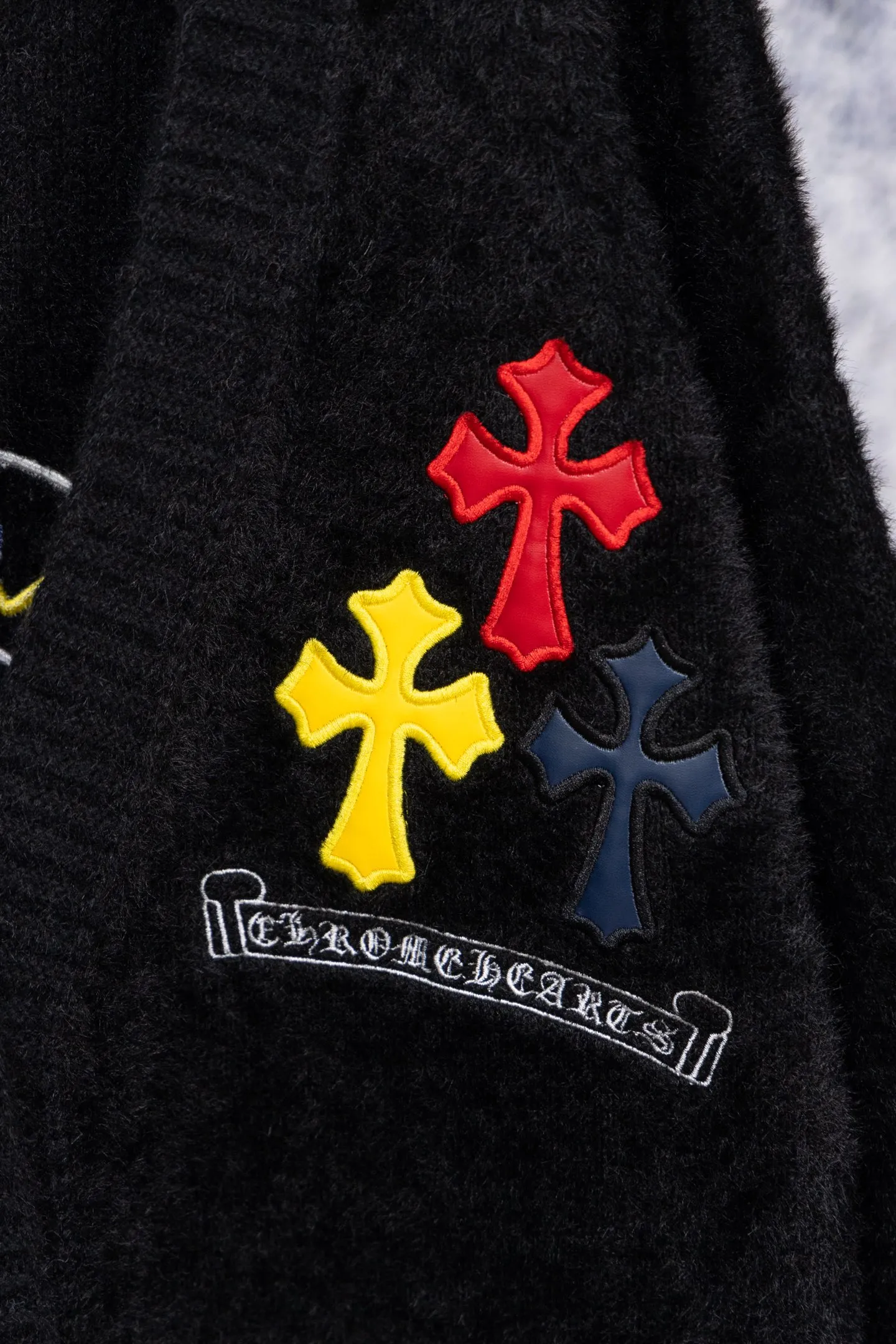 P300 Chrome Hearts CH Chrome Hearts 2026 new cross loose knitted V-neck cardigan Fabric: Made of plush textured knitted material, soft to the touch and with a lazy atmosphere; Decoration: Red, yellow, and black cross ornaments on the chest, paired with brand logo patches, which are iconic elements of street fashion brands (such as Chrome Hearts style), enhancing visual recognition; Version: Loose version + single-row metal button design, combining casual feeling and practicality. 2. Style and Adaptation Style: It combines dark street style and gentle knitted texture, which belongs to the tone of "sweet and cool mix"; Scenario: Can be worn with a T-shirt/suspender to create a daily street look, or can be layered with a shirt for light casual wear. Color: Black White Size: M L XL